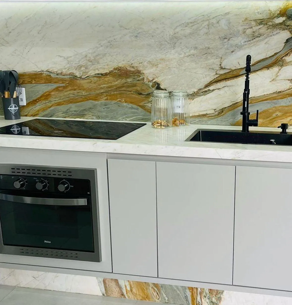 Cozinha com bancada e frontão em Dolomítico Calacata Milano Oro