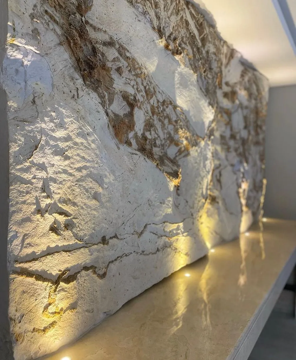 Parede escultórica em rocha natural com iluminação rasante